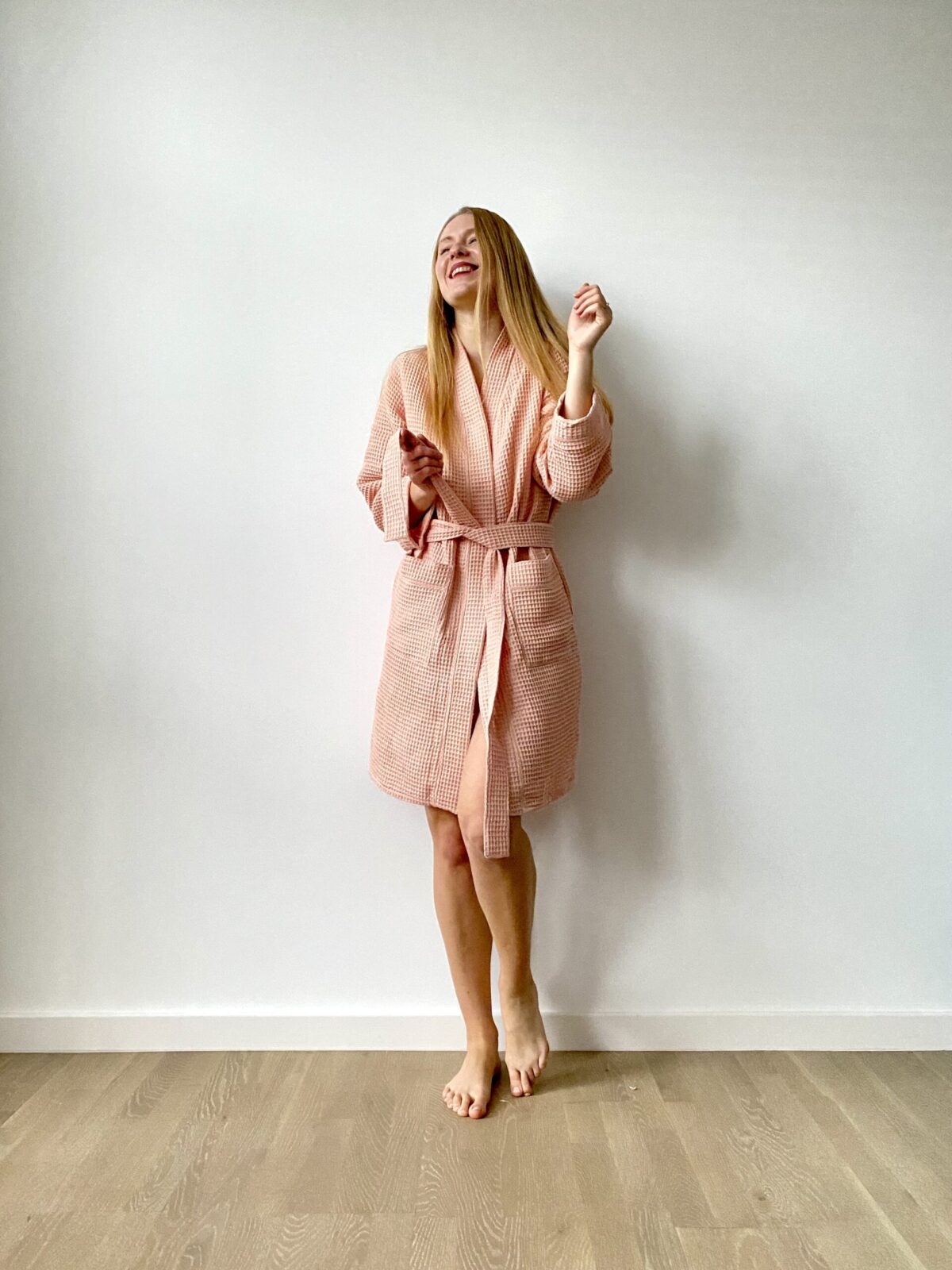 Woman wearing a short waffle cotton bathrobe with tie waist and pockets, perfect for home or spa lounging.