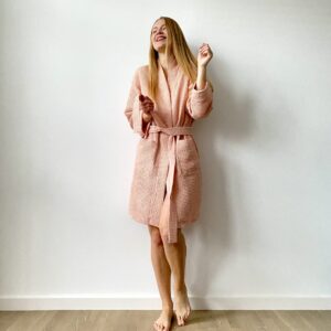 Woman wearing a short waffle cotton bathrobe with tie waist and pockets, perfect for home or spa lounging.