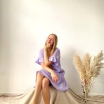 Woman wearing short lilac muslin ruffle dress with flared sleeves and hem, perfect for summer comfort and style.