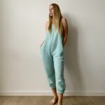 Woman wearing an organic muslin lounge jumpsuit in airy cotton with relaxed fit, pockets, and minimalist design.