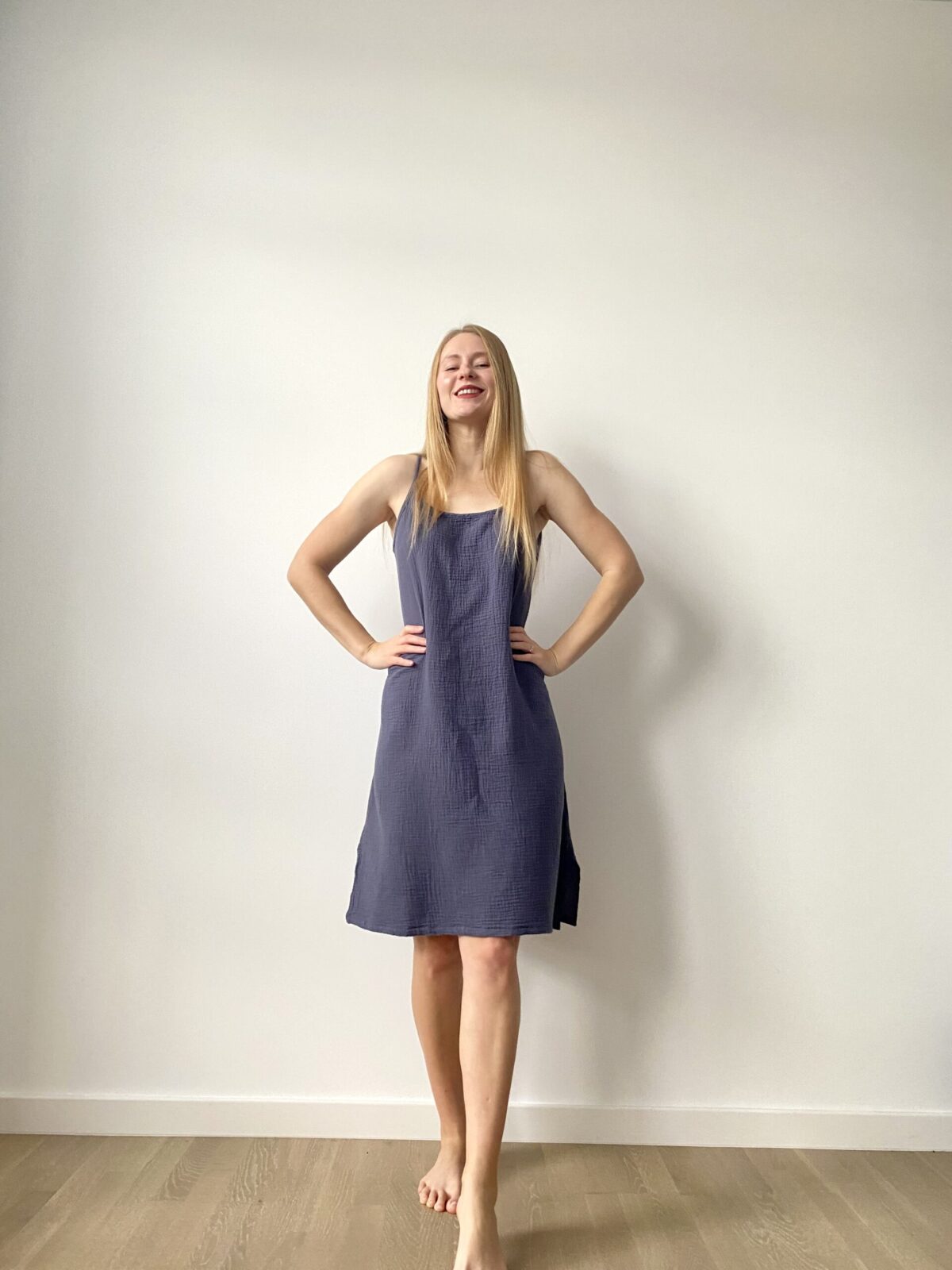 Woman in sleeveless mini muslin slip dress with relaxed silhouette, front and back views.