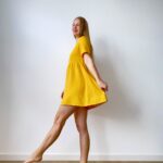 Woman in a short-sleeve muslin babydoll mini dress twirling with a relaxed, flowy silhouette.