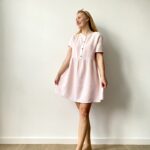 Woman wearing a short-sleeve, pastel muslin button-front mini dress with a flared skirt.