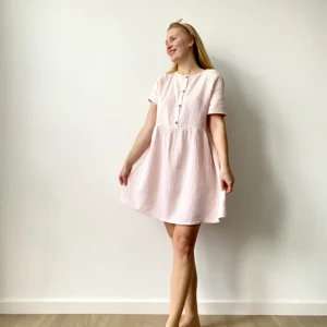 Woman wearing a short-sleeve, pastel muslin button-front mini dress with a flared skirt.