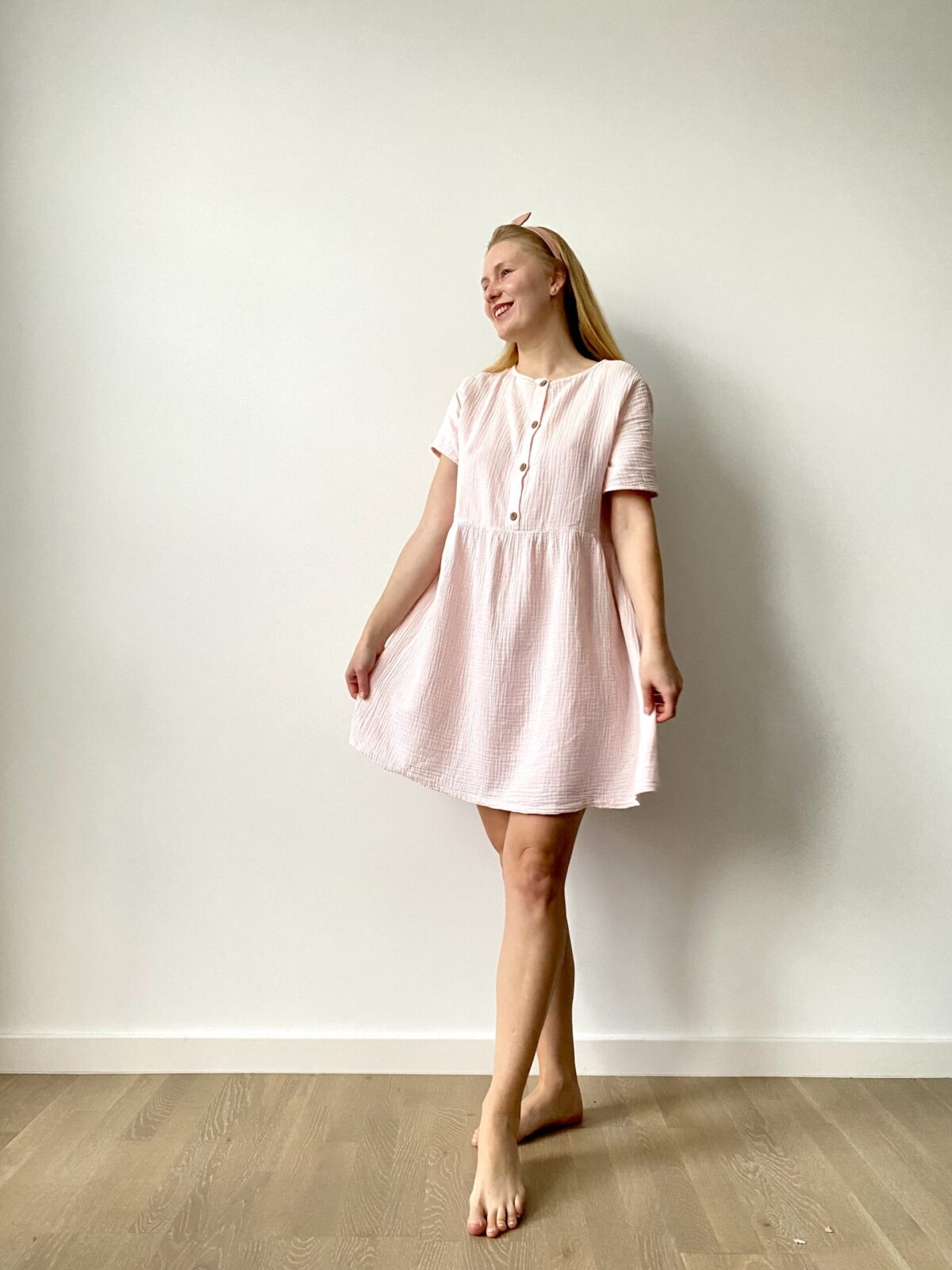 Woman wearing a short-sleeve, pastel muslin button-front mini dress with a flared skirt.