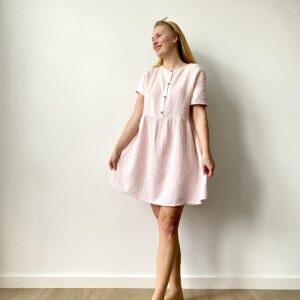 Woman wearing a short-sleeve, pastel muslin button-front mini dress with a flared skirt.