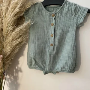 Natural cotton muslin jumpsuit for babies with short sleeves, wooden buttons, and soft gathered legs.