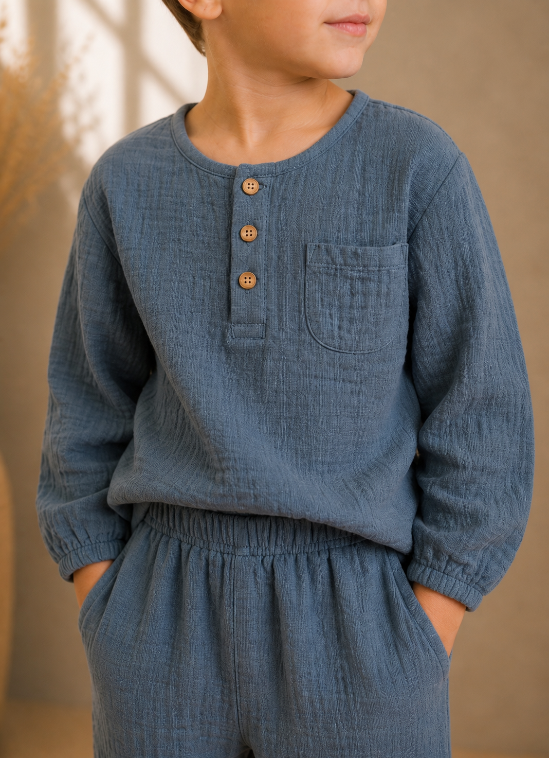 Close up boy wearing handmade organic cotton muslin long-sleeve top and matching trousers set