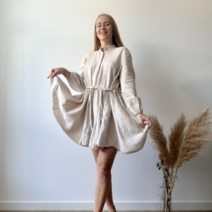 a light beige handmade muslin shirt dress with long sleeves and a tie waist