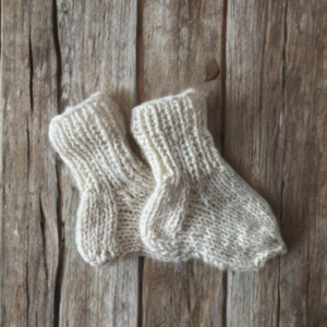 Cream-colored hand-knitted kids’ socks made from natural sheep wool