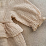 Neutral muslin dress for baby with tiered skirt and puffed sleeves