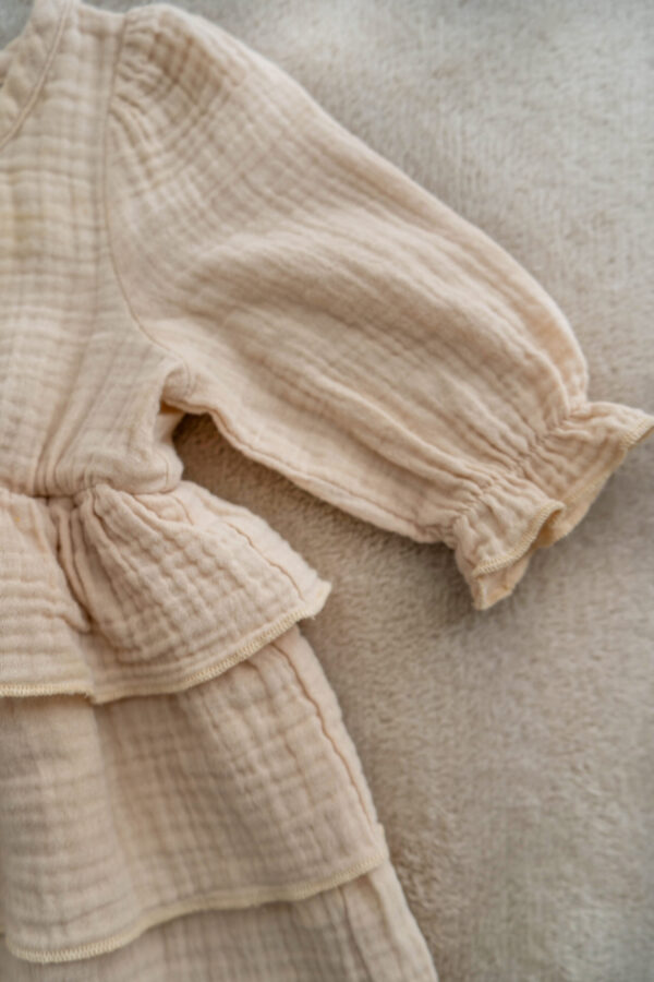 Neutral muslin dress for baby with tiered skirt and puffed sleeves