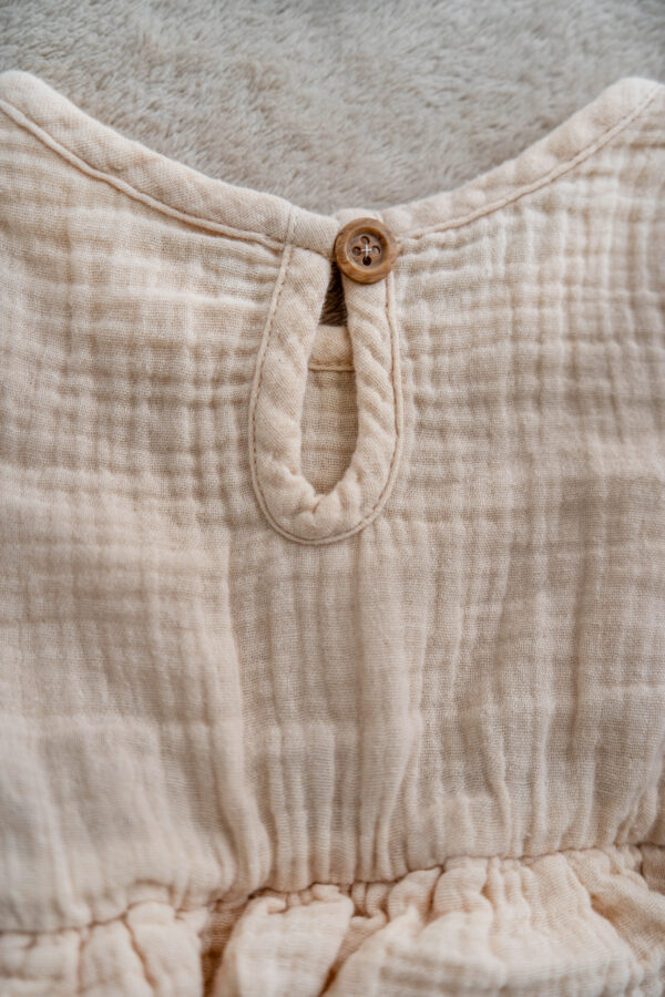 long-sleeve baby dress in natural muslin with gathered waist and frill details