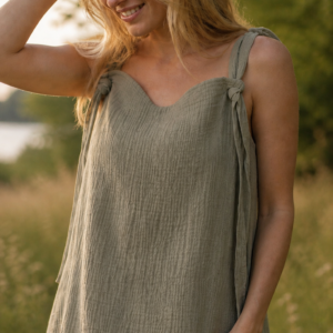 Woman wearing handmade organic cotton muslin pocket dress in sage green with adjustable tie straps