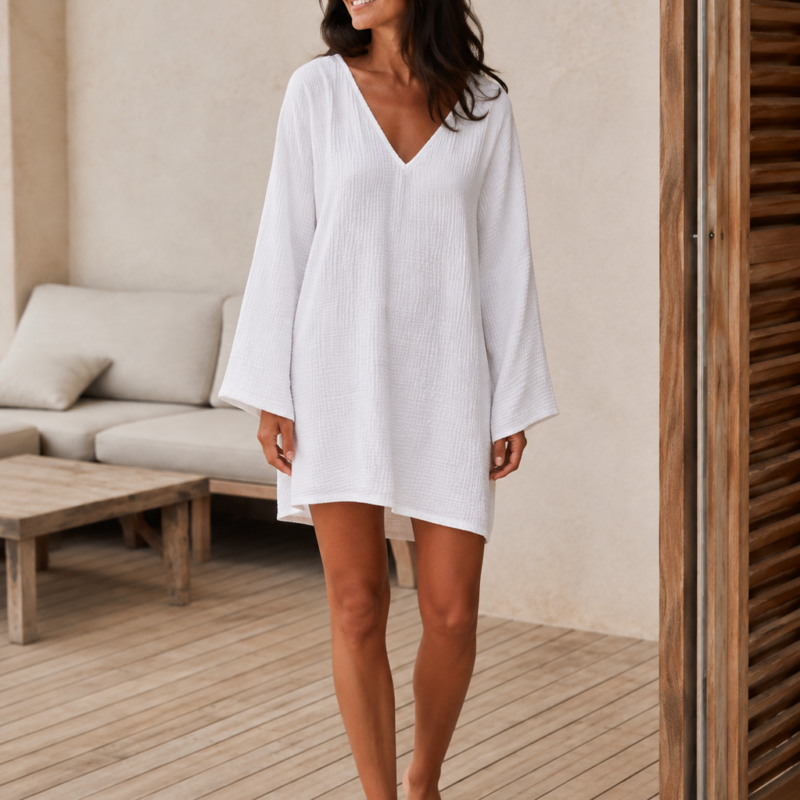 Woman wearing a relaxed cotton muslin beach cover-up dress with V-neckline and wide long sleeves - front
