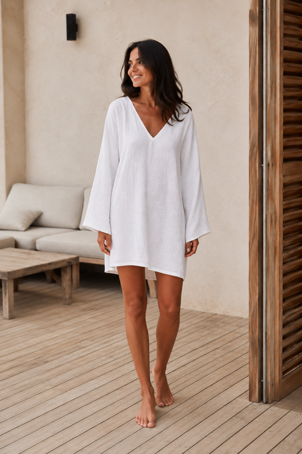 Woman wearing a relaxed cotton muslin beach cover-up dress with V-neckline and wide long sleeves - front