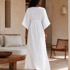 Woman wearing a flowing cotton muslin maxi dress with V-neckline, relaxed sleeves and side slit - back