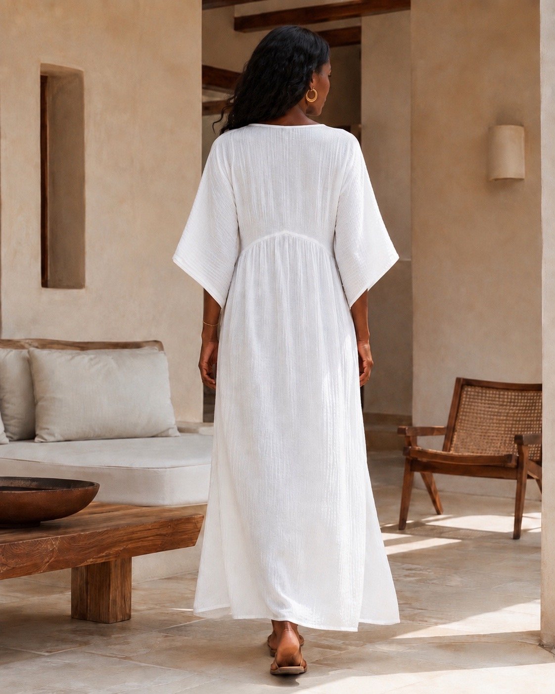Woman wearing a flowing cotton muslin maxi dress with V-neckline, relaxed sleeves and side slit - back