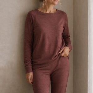 Woman wearing a burgundy merino wool lounge set with a long-sleeve top and matching trousers - close up