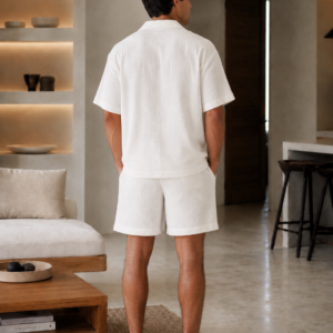 Man wearing a white cotton muslin set with a short-sleeve button shirt and matching relaxed shorts - back