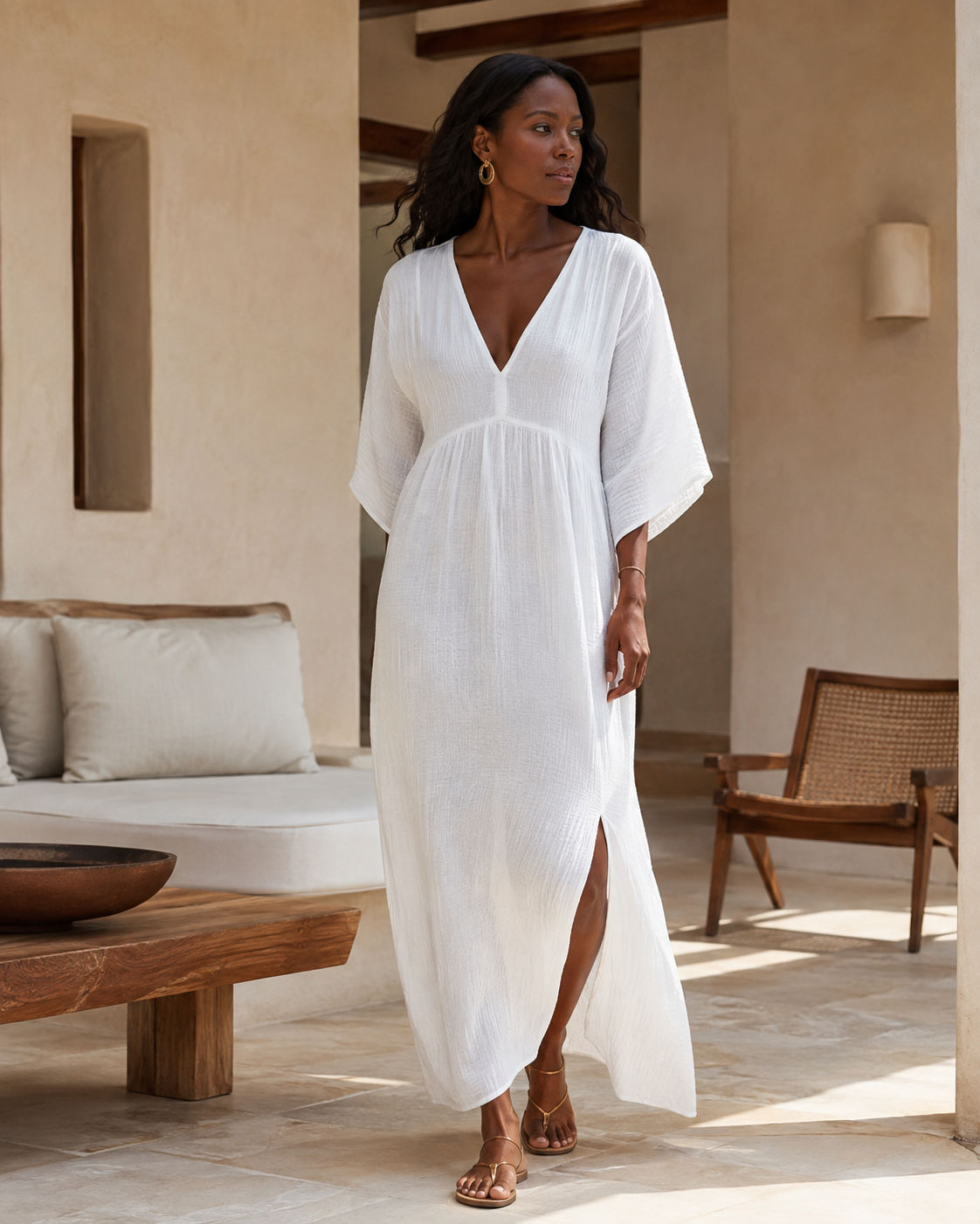 Woman wearing a flowing cotton muslin maxi dress with V-neckline, relaxed sleeves and side slit - front
