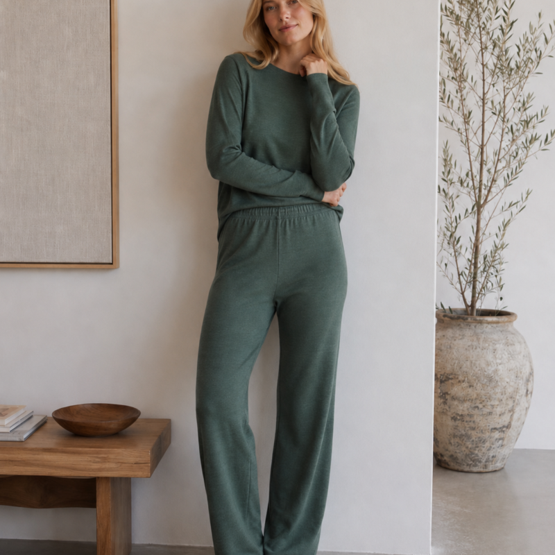 Woman wearing a green merino wool lounge set with a long-sleeve top and relaxed straight-leg trousers - front