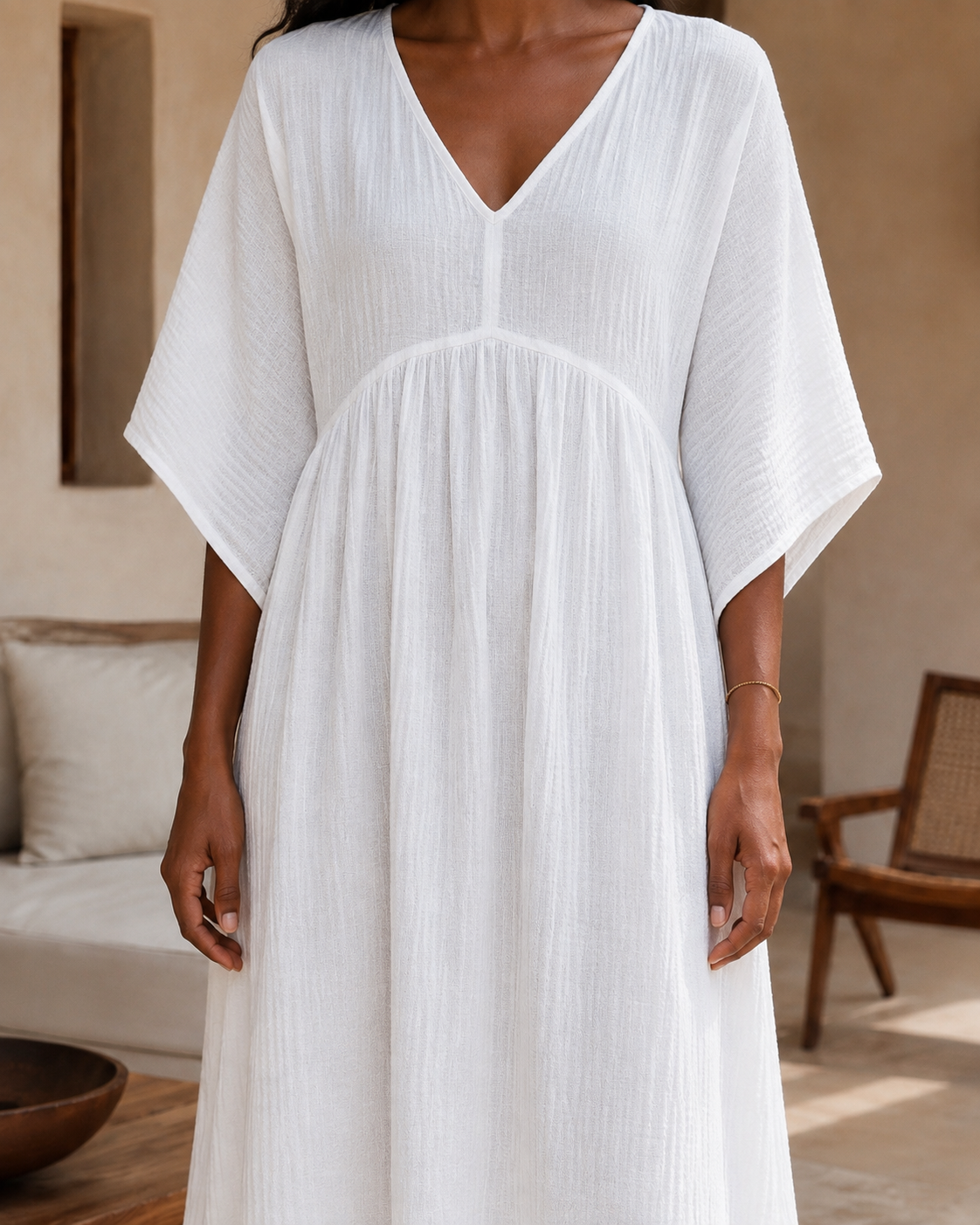 Woman wearing a flowing cotton muslin maxi dress with V-neckline, relaxed sleeves and side slit - close up